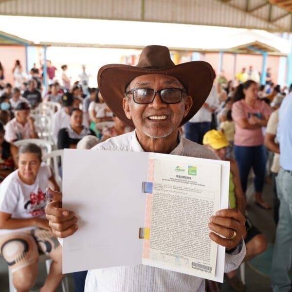 Investimentos- Um senhor de aproximadamente 65 anos mostrando o documento de regularização fundiária de seu imóvel