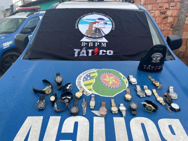 Relógios apreendidos sobre capô da viatura policial do Grupo Tático da PMGO