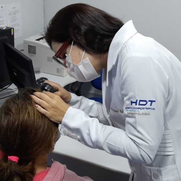 Médica do HDT examinando a pele de uma paciente com uma lupa.