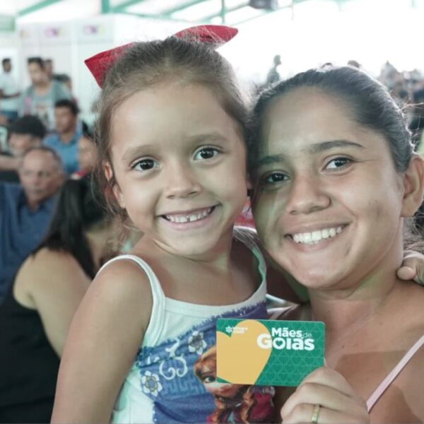 Mulher e criança seguram cartão Mães de Goiás