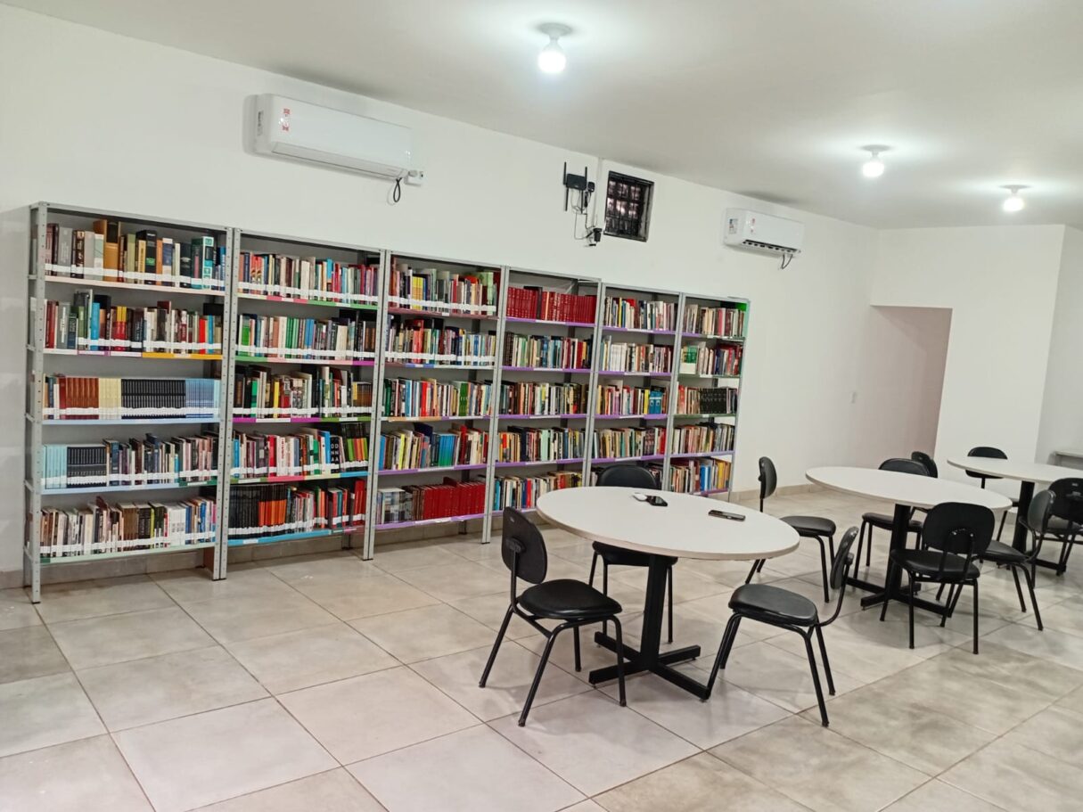 Secult doa de mais de mil livros para biblioteca municipal de Baliza - Espaço interno da biblioteca com estante de livros, mesas redondas brancas e cadeiras pretas